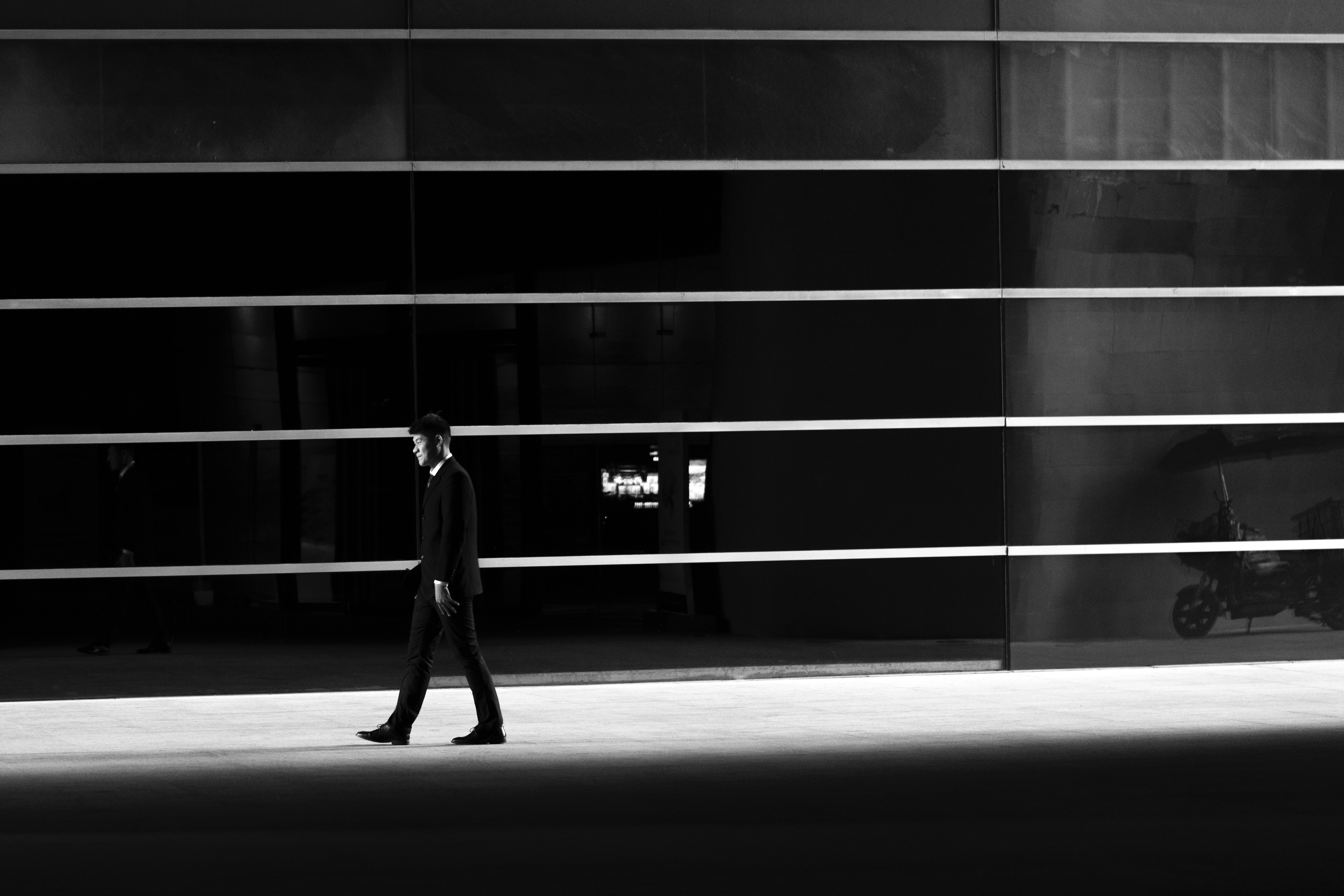 man in suit walking in front of building appearing to be in visual layers